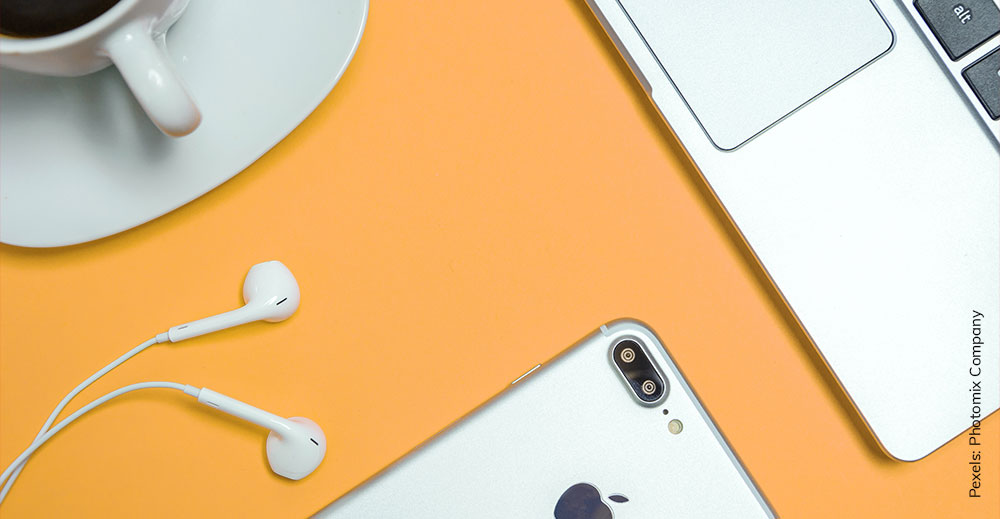 Ein gelber Hintergrund mit einem Laptop, einem Smartphone und einer Kaffeetasse