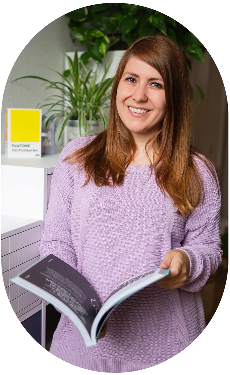 Kathrin Schönborn lächelt in die Kamera und hat dabei ein Buch in der Hand